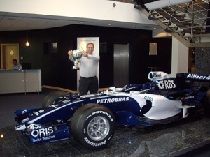 me holding the constructors\' trophy next to a Williams F1 car