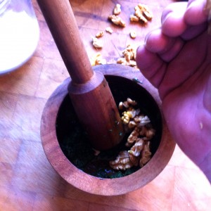 5. Grind the basil into pulp, add your crushed walnuts, and keep grinding.